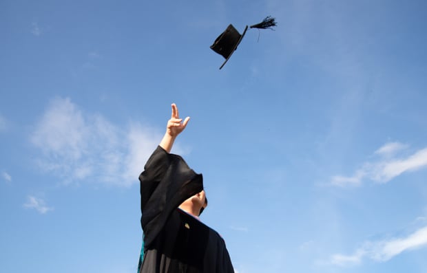 Individual throwing their graduation cap in the air.